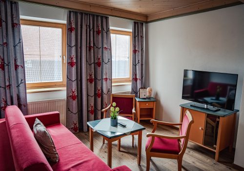 Gemütliche Sitzecke mit roter Couch und Fernseher