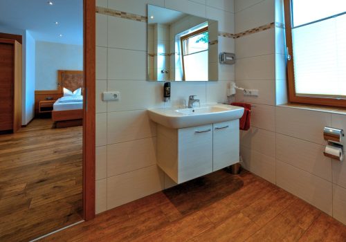 Offene Tür im Bad mit Blick auf das Waschbecken und Bett